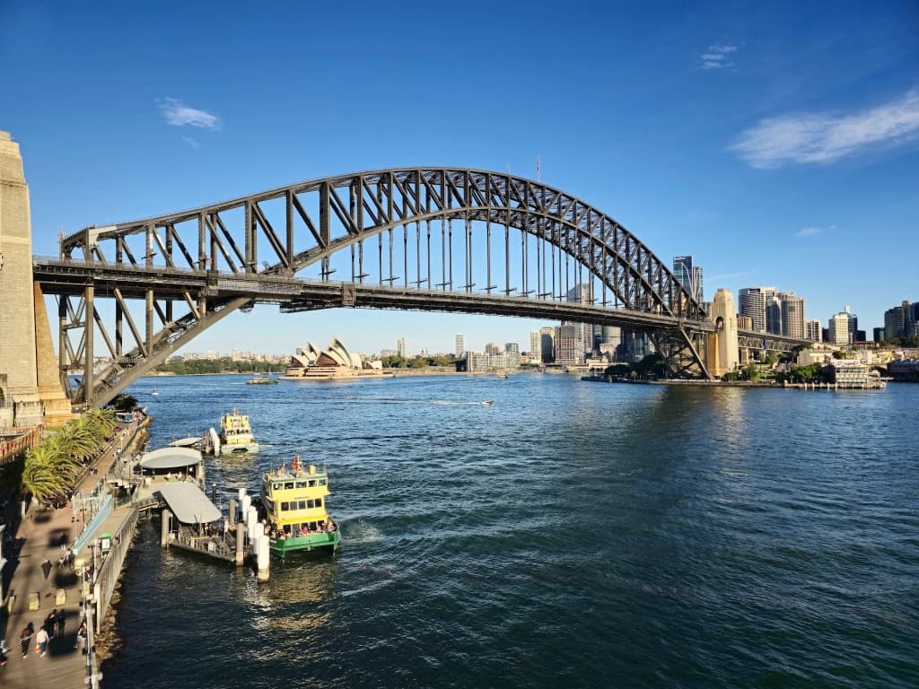 Looking up at the massive steel structure of the Sydney Harbour Bridge against a blue sky