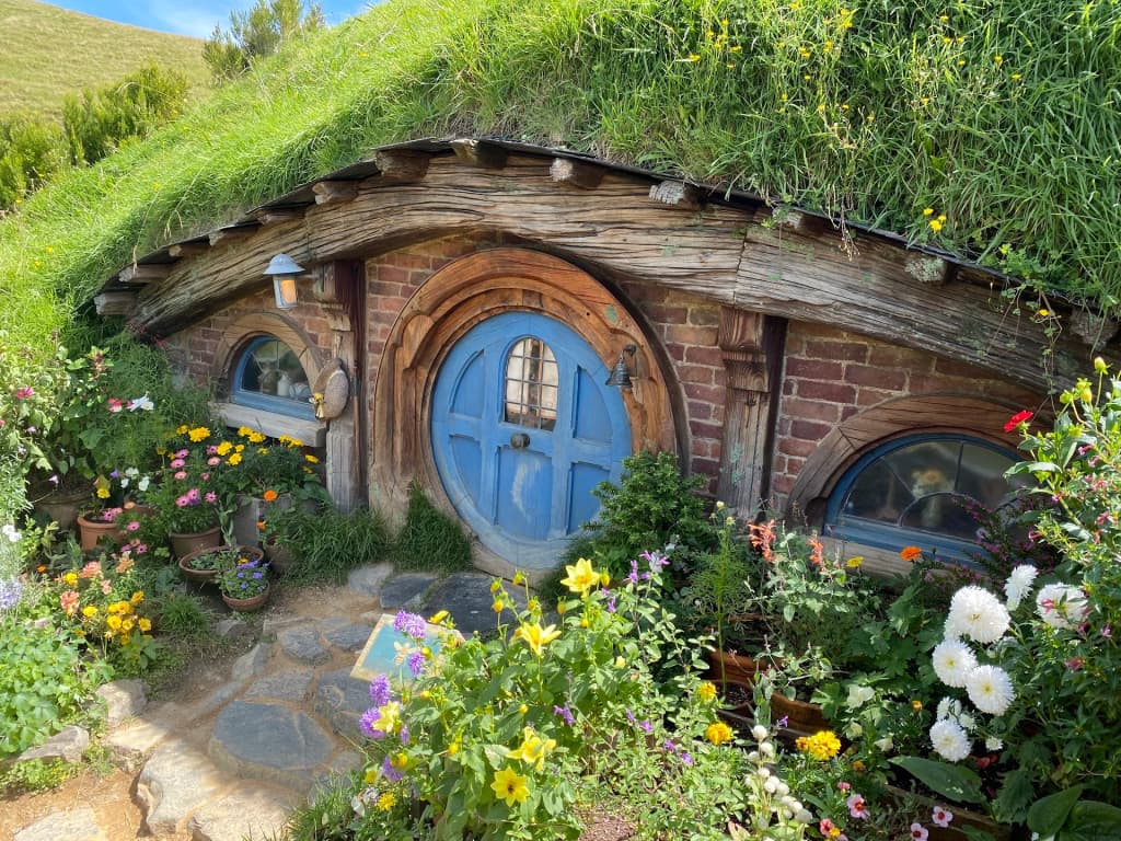 A picturesque Hobbit hole built into the lush green hills of the Shire