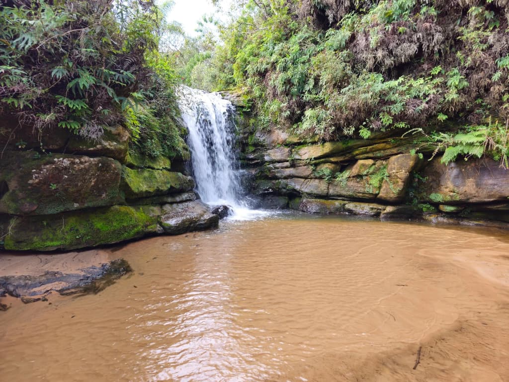 Inside Buraco do Padre cave, sunlight beaming onto the waterfall