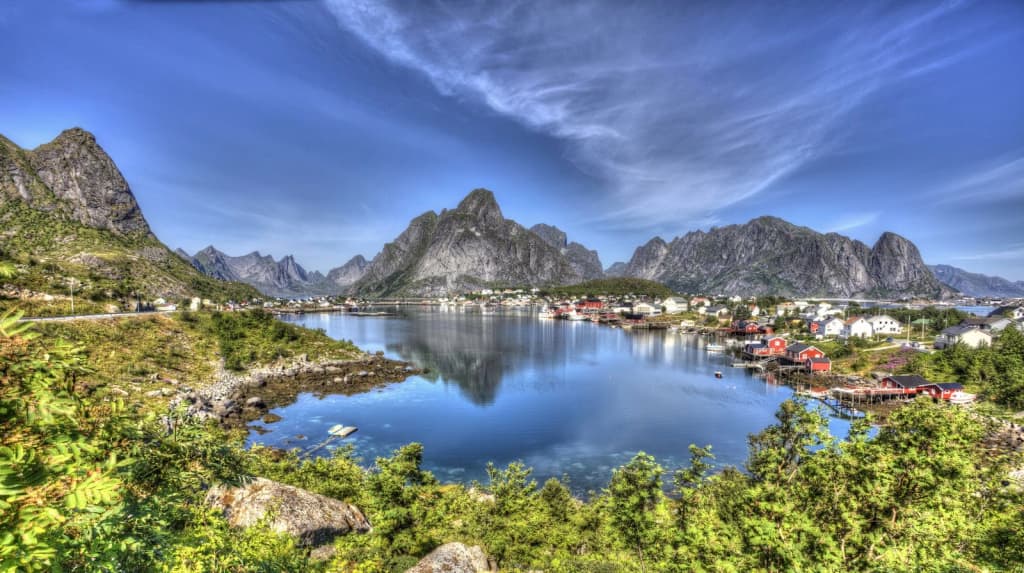 Dramatic red fishing houses beneath the towering peaks of Reine