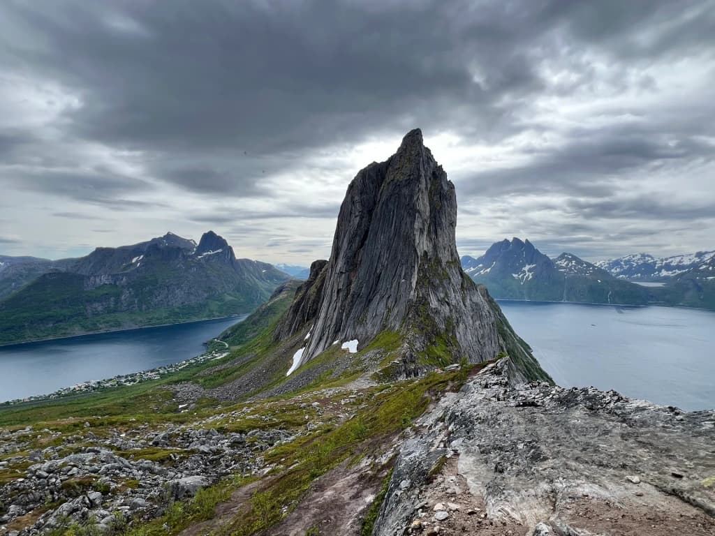 The massive sheer cliffs of Segla mountain rising from the dark Arctic sea