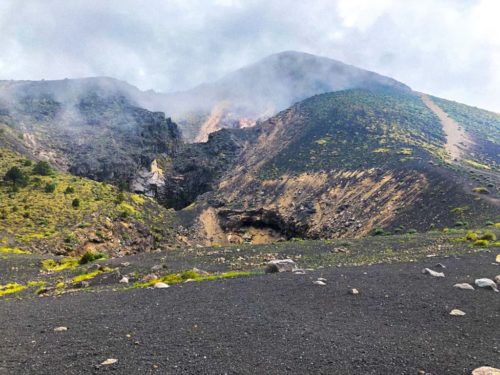Hikers at Acatenango base camp with Fuego volcano in the distance