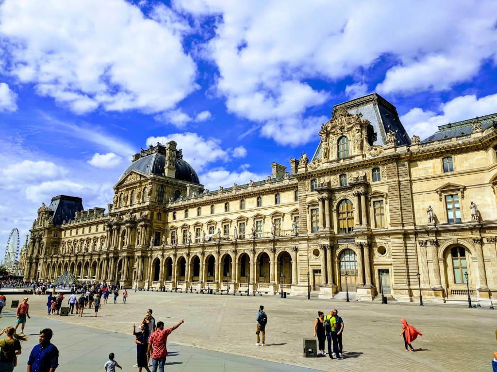 The grand glass pyramid of the Louvre Museum glowing against the Parisian sky