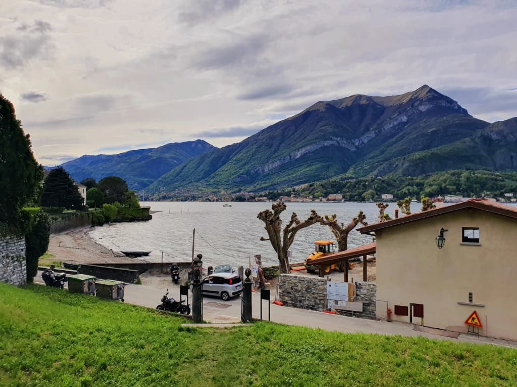 A scenic view of Bellagio's waterfront promenade with boats docked and mountains in the background