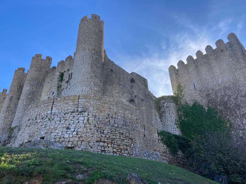 The towering stone walls of Castelo de Óbidos against a clear sky