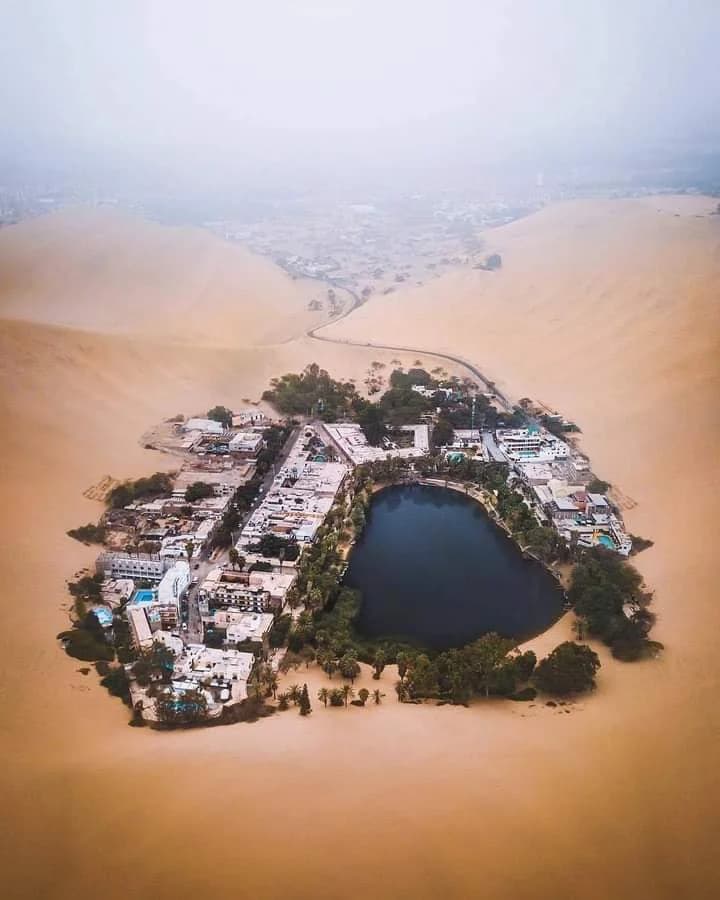 Towering sand dunes surrounding the Huacachina Oasis in the Peruvian desert