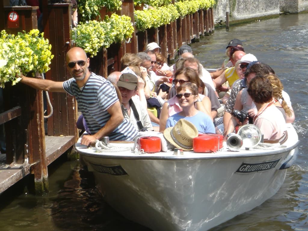 Una barca navegando los canales medievales de Brujas
