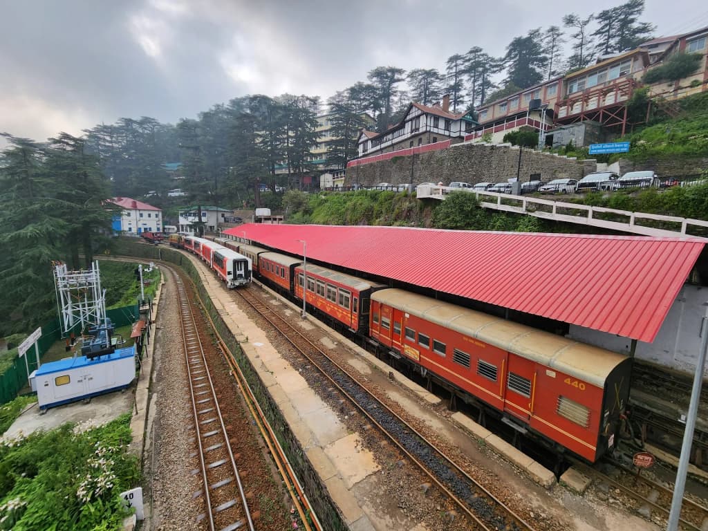 El histórico tren Himalayan Queen avanzando entre montañas cubiertas de cedros rumbo a Shimla