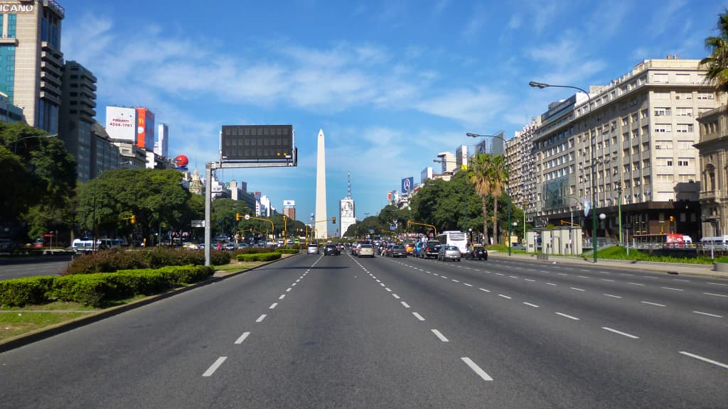 The sprawling lanes of 9 de Julio Avenue blur with the motion of city traffic under the bright Argentine sun