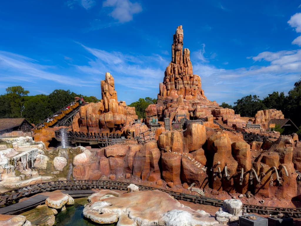 The rusted red rock formations of Big Thunder Mountain Railroad against a bright Florida sky