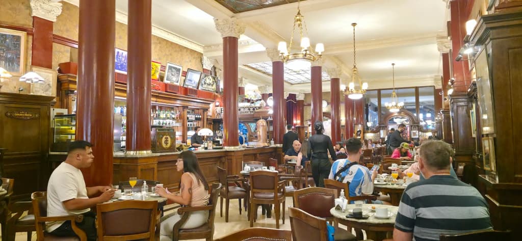 The ornate, warm-lit interior of Café Tortoni with its historic wooden tables