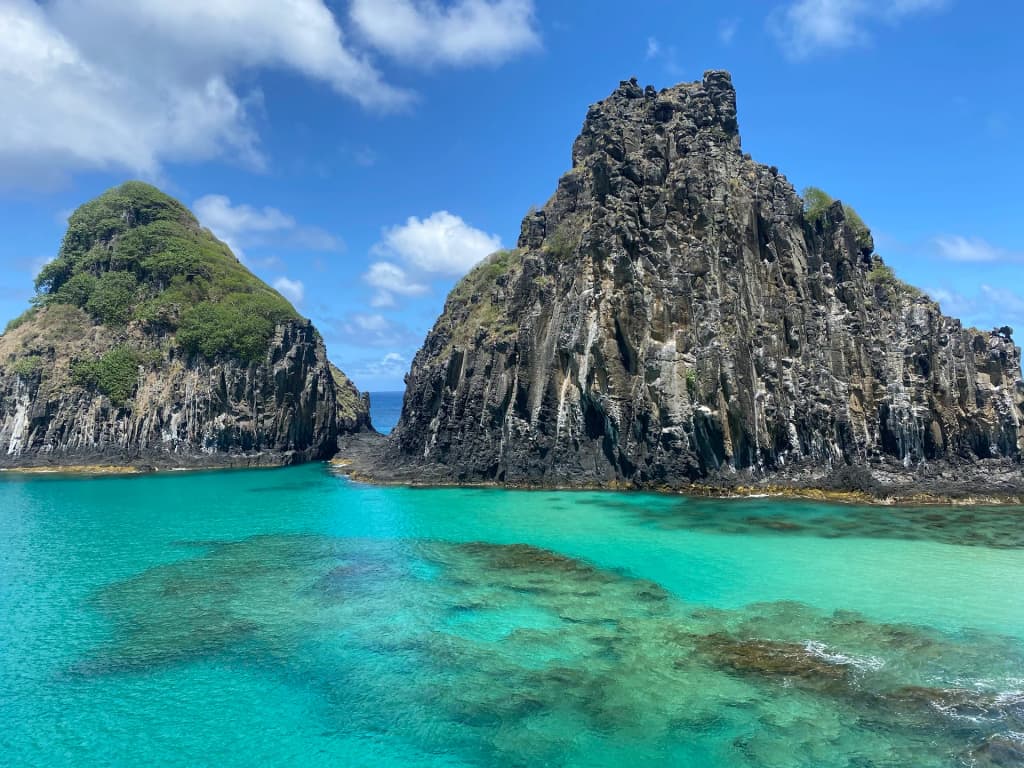 Crystal clear tidal pools at Baía dos Porcos with rugged cliffs in the background