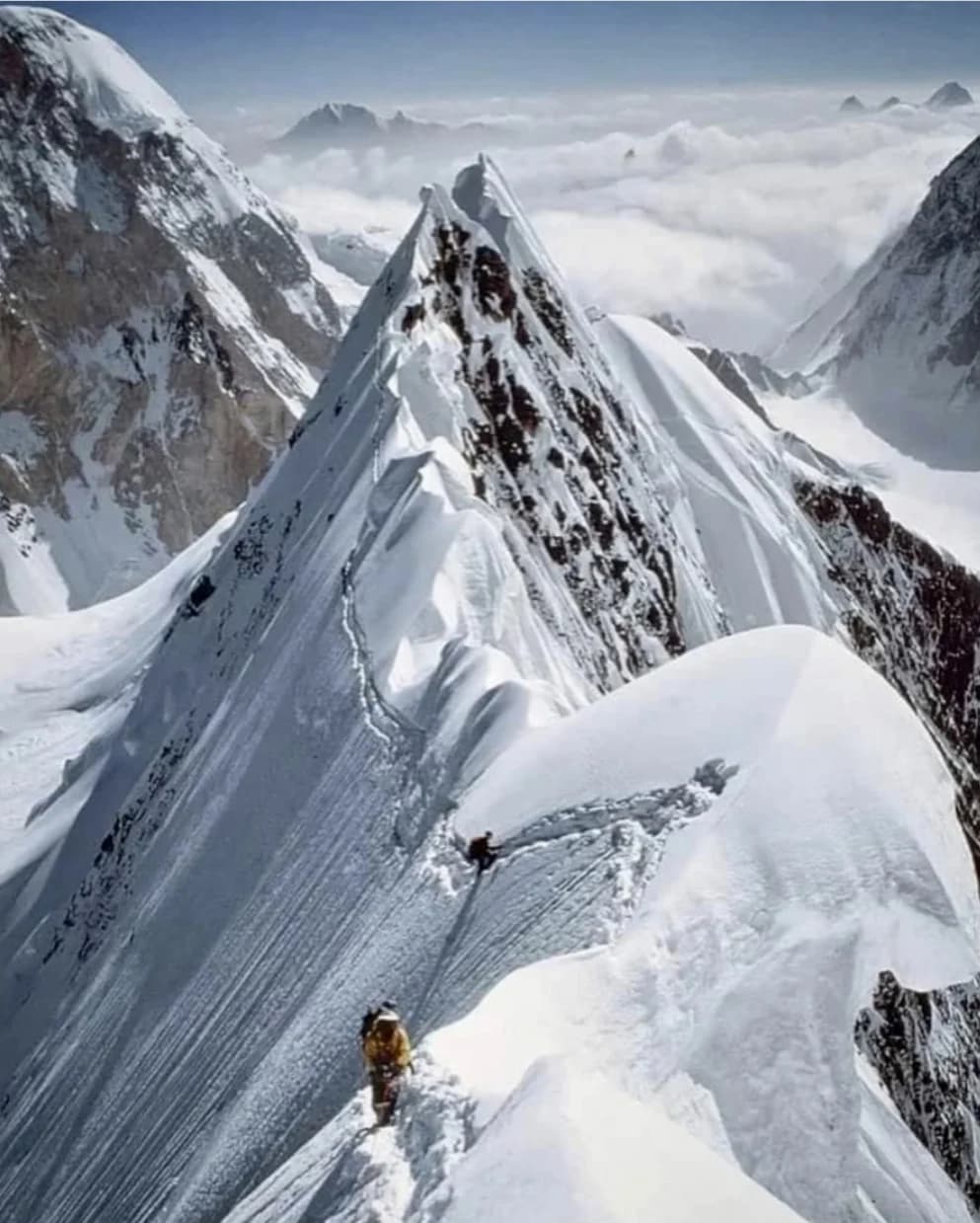 Climbers set up camp on the Baltoro Glacier, dwarfed by the icy mass of K2