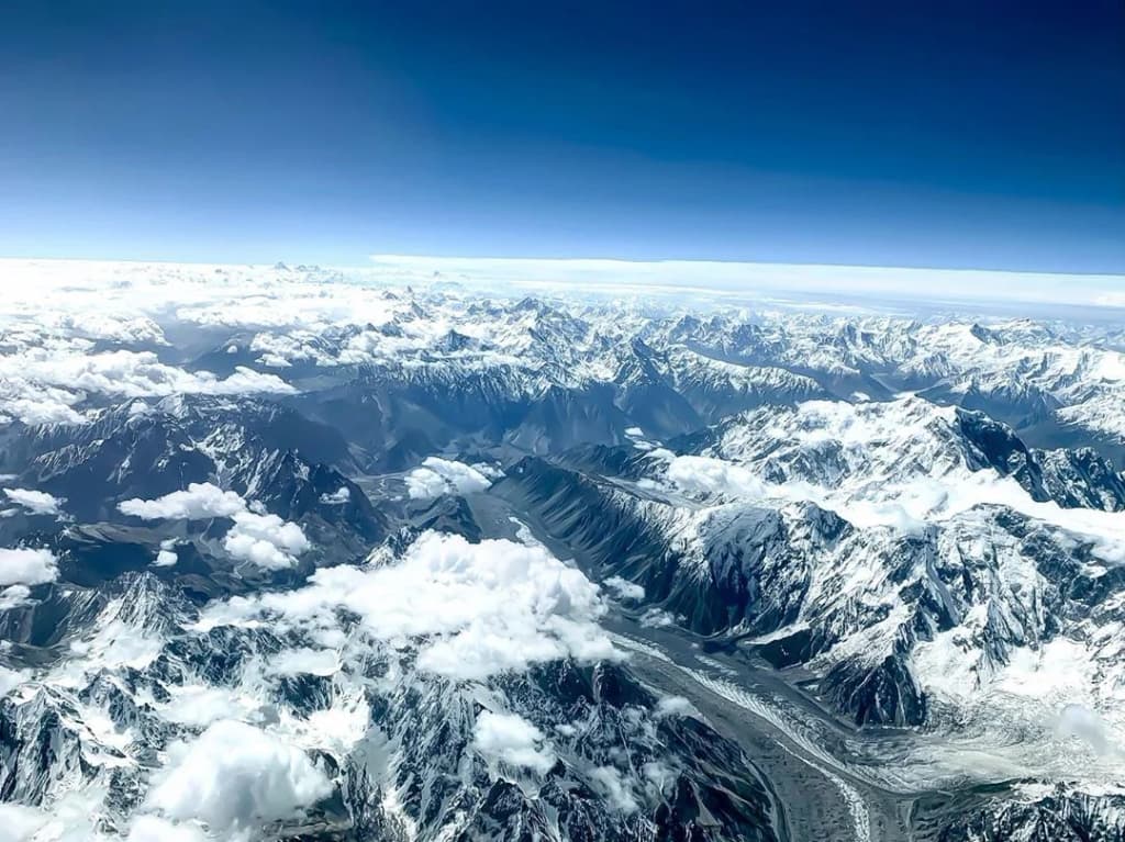 A wildflower-strewn meadow in Deosai National Park, with snow-capped peaks in the distance