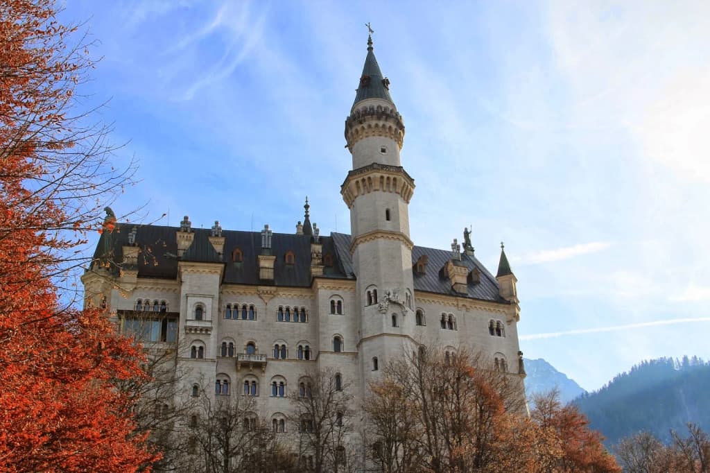 View of Neuschwanstein Castle from Marienbrücke, surrounded by forest and waterfalls