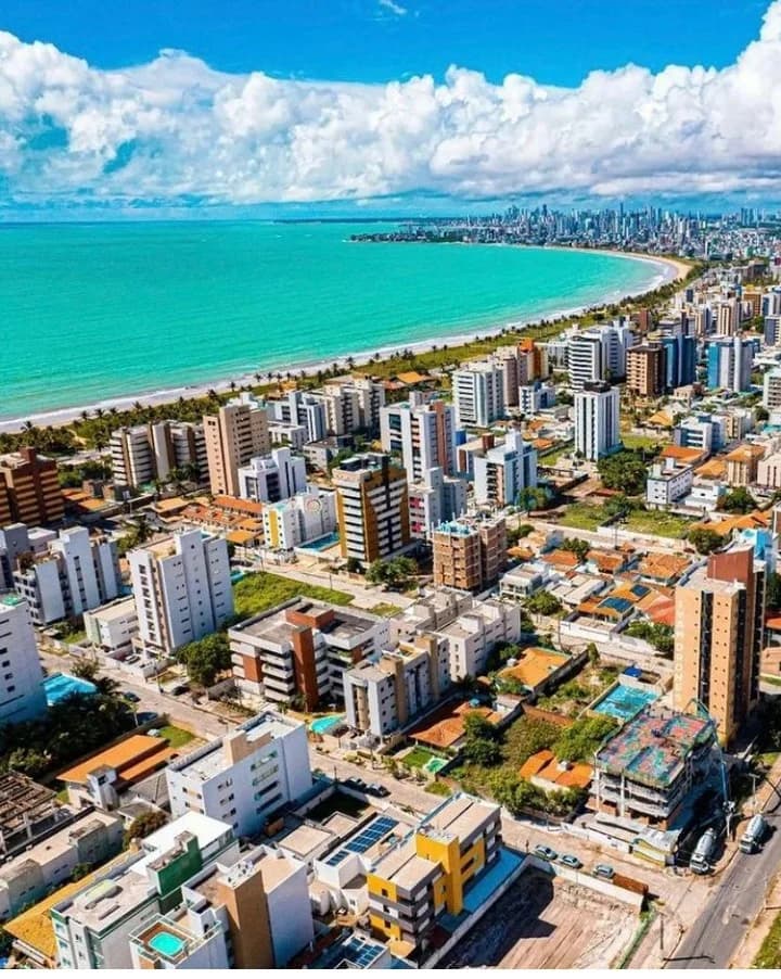 Amanecer dorado sobre la costa de João Pessoa, olas brillando, ciudad despertando