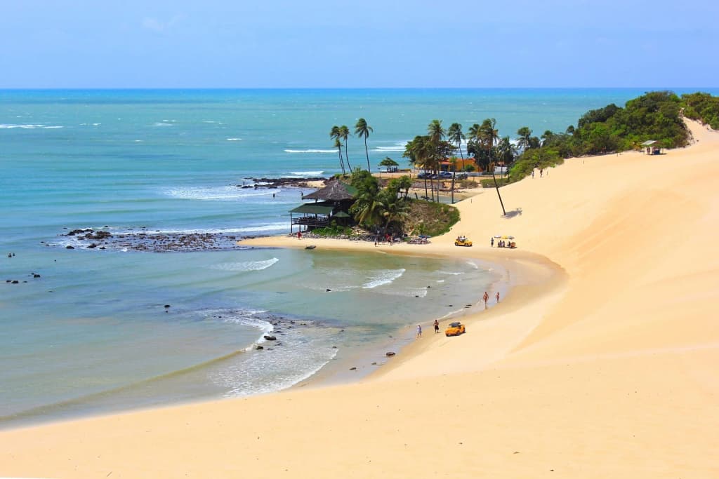 Dunas de Genipabu com trilhas de buggy e céu dramático