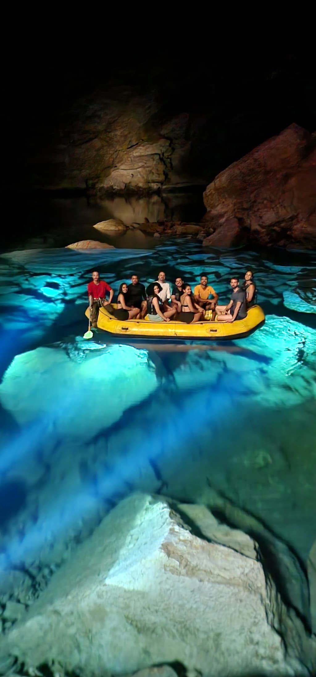 Grupo de aventureros cruzando una piscina subterránea cristalina en una cueva enorme