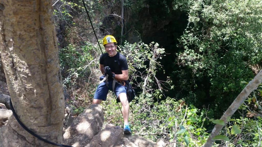 Grupo haciendo rappel en un sumidero gigante y verde con bosque en el fondo