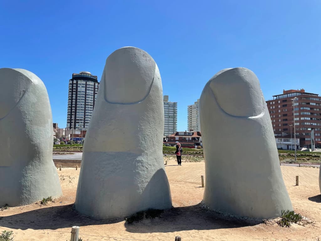 A escultura Los Dedos emergindo da areia na Playa Brava, Punta del Este