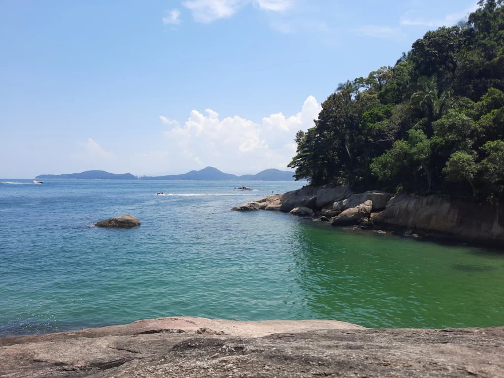 Vista da Praia do Sangava cercada por morros verdes exuberantes