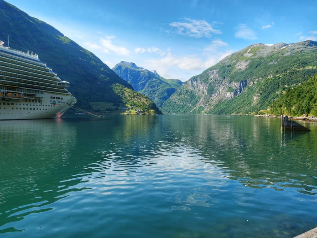 A ferry gliding beneath waterfalls in Geirangerfjord