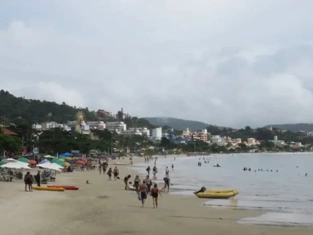 Fisherman on Bombinhas beach at sunrise, net in hand, misty light