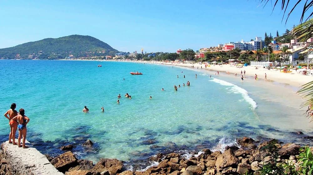 Golden hour on Bombinhas beach, families strolling, sky streaked with pink