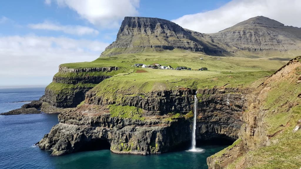 Dramatic cliffs and green-roofed houses of the Faroe Islands