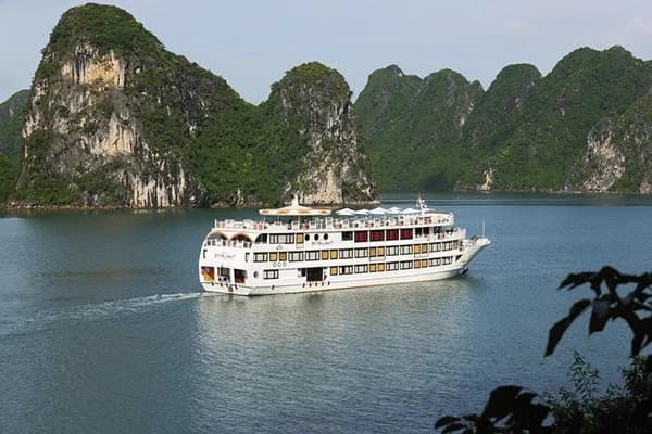 Navio de cruzeiro em Halong Bay ao pôr do sol, ilhas ao fundo