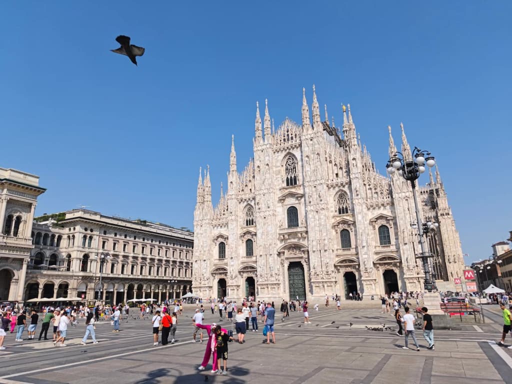 The Duomo di Milano bathed in morning light, crowds and pigeons in the square
