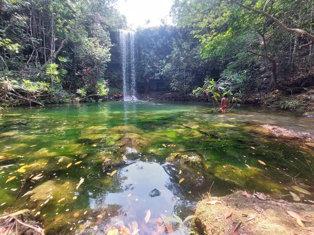 Hikers crossing a wild, rocky stream in the Cerrado
