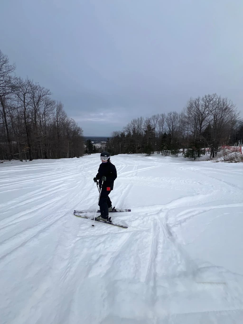 Hiker standing on Trolltunga, rock ledge over blue lake